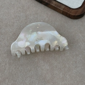 Close-up of pearl white acetate hair claw clip with Barrette la France logo engraving