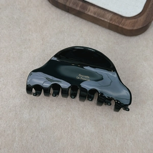 Close-up of glossy black acetate hair claw with gold Barrette La France lettering detail