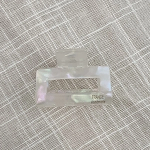 Detailed shot of rectangle acetate hair claw with cream mother-of-pearl texture and handmade logo