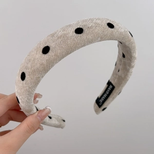 Detail view of handmade beige headband with black polka dots and soft velvet texture
