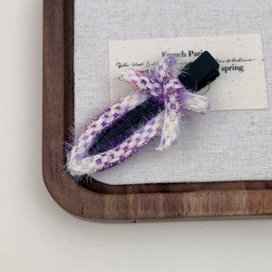 Pince à cheveux tissée violette et blanche avec nœud sur un plateau en bois