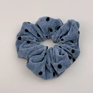 Texture détaillée d'un chouchou en velours côtelé bleu-gris à pois noirs