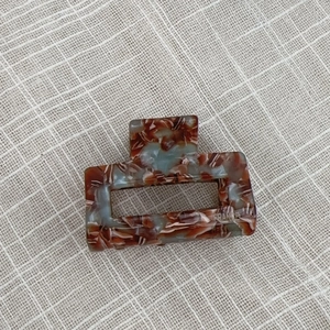 Detail view of handmade marble acetate hair claw clip on neutral fabric background