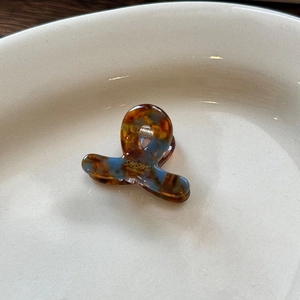 Mini molletta per capelli in acetato con motivo tartarugato e logo dorato su vassoio