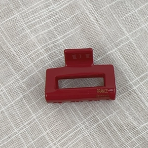 Detail of red hollow acetate hair claw clip with golden France Handmade lettering