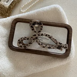 Detail shot of a large leopard print hair claw clip on a stylish wooden tray display