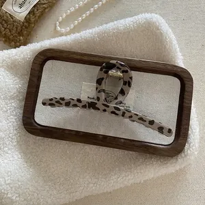 Close-up of leopard print hair claw clip on tray with elegant pearl necklace detail
