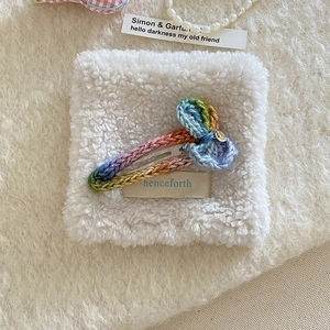 Handmade rainbow crochet heart hair clip with bow on a cozy white plush background