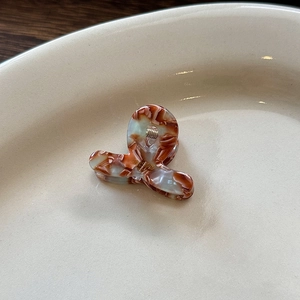 Dettaglio di una piccola molletta per capelli in acetato tartarugato su un vassoio