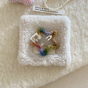 Detail of a handmade rainbow knit star hair clip with cartoon rabbit cotton tag