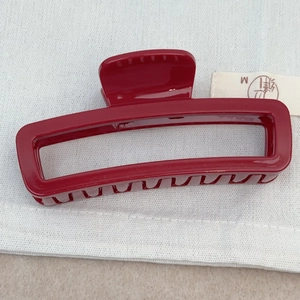 Vue détaillée de la pince à cheveux rectangulaire minimaliste rouge foncé sur tissu