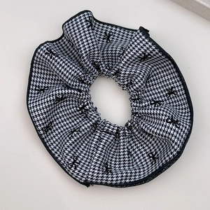 Detail eines großen Houndstooth-Scrunchie mit schwarzem Schleifenmuster und Stoffstruktur