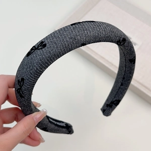 Détail du serre-tête tressé gris avec nœuds noirs et étiquette faite à la main