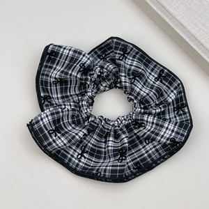 Detail eines karierten Scrunchies mit schwarzer Schleifenstickerei und feiner Textur