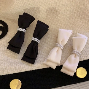 Elegant satin bow hair clips with pearls in black and cream on tweed background
