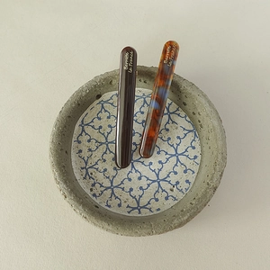 Close-up of minimalist acetate hair clips in solid brown and mottled tortoiseshell patterns