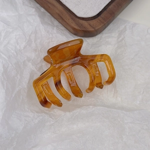 Detailed macro view of an amber resin hair claw clip with France Handmade engraving