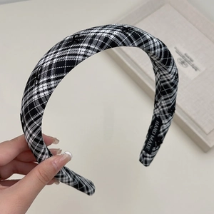 Nahaufnahme des schwarz-weiß karierten Stoff-Haarreifs mit Hand-Made-Webetikett