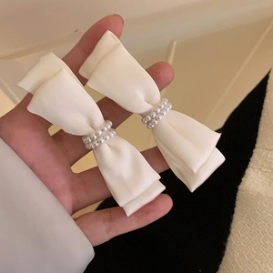 Detail view of two cream satin bow hair clips with elegant faux pearl embellishments