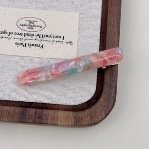 Close-up of marble pattern acetate hair clip with gold La France lettering and metal grip