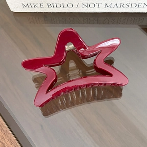 Detail view of burgundy star-shaped hair claw clip with golden metal spring
