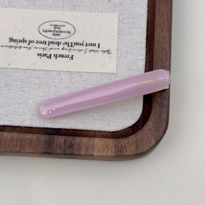 Close-up of a slim light purple acetic acid hair clip with gold lettering on wood