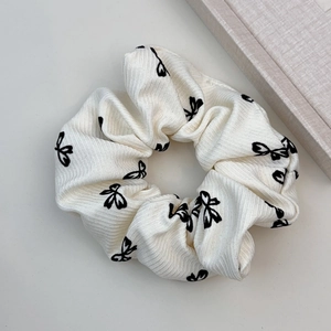 Détail d'un chouchou crème avec motif de nœud noir et texture de tissu côtelé élégant