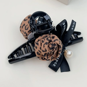 Detail of a black hair claw clip featuring leopard print roses and a pearl pendant