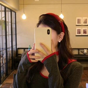 Vintage red velvet headband with gold bow accent for women, shown in elegant cafe setting