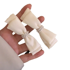 Pair of cream satin bow hair clips featuring elegant double-row pearl center decorations