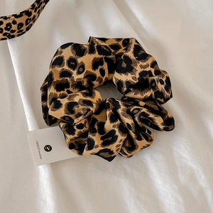 Close-up of leopard print hair scrunchie and matching headband with soft fabric texture