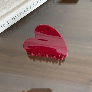 Detailed close-up of a burgundy heart-shaped hair claw clip with glossy resin finish