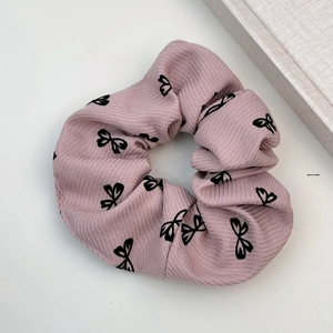 Vue détaillée d'un chouchou plissé rose clair avec des motifs de nœuds noirs