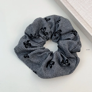 Détail d'un chouchou gris en tricot avec imprimé papillon noir sur fond blanc