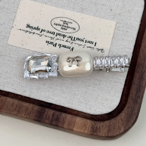 Close-up of zircon bow hair clip with smoky grey crystals and cream square accents