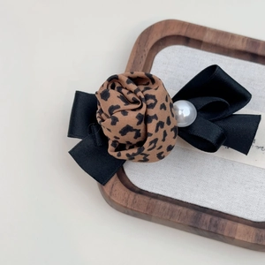Detail of leopard print fabric rose hair clip with black ribbon bow and white pearl