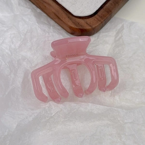 Close-up of pink jelly hair claw clip with France engraving on polished resin surface