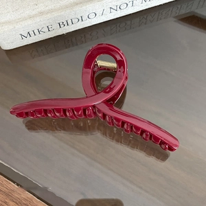 Macro detail of glossy burgundy cross hair claw clip with golden metal spring