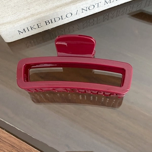Close-up of a burgundy rectangular hair claw clip with a glossy minimalist hollow frame