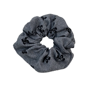 Chouchou en tricot gris moyen avec motif de nœuds noirs sur fond blanc épuré