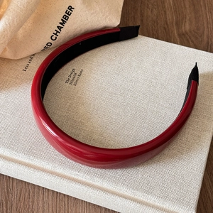 Close-up of elegant wine red leather headband with glossy finish on a book