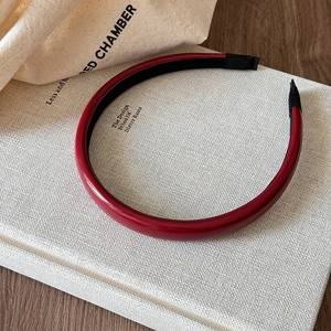 Close-up of glossy deep red headband with non-slip black lining on white book background