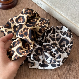 Gros plan de chouchous en satin à imprimé léopard marron et gris, texture soyeuse