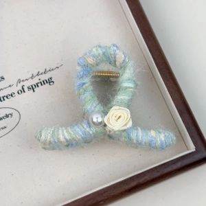 Détail de la pince à cheveux en laine tricotée avec fleur et perle décorative