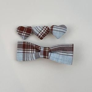 Detail showing fabric heart and bow hair clips with blue and brown plaid patterns