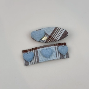 Detail of blue plaid fabric hair clips featuring 3D heart charms and golden metallic tag