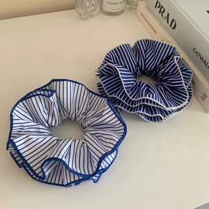 Blue and white striped oversized scrunchie set with ruffle edge on a white desk