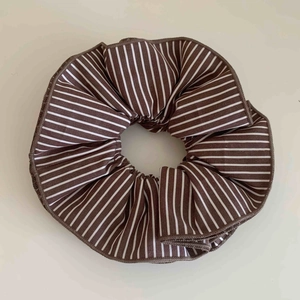 Classic brown and white striped fabric scrunchie with layered pleats on a neutral surface