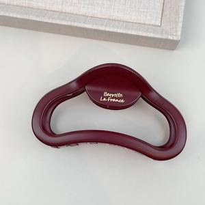 Macro shot of matte burgundy hair claw with gold Barrette La France lettering