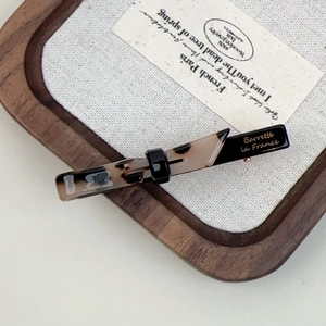 Detail of a rectangle barrette featuring tortoiseshell pattern and black acetate finish